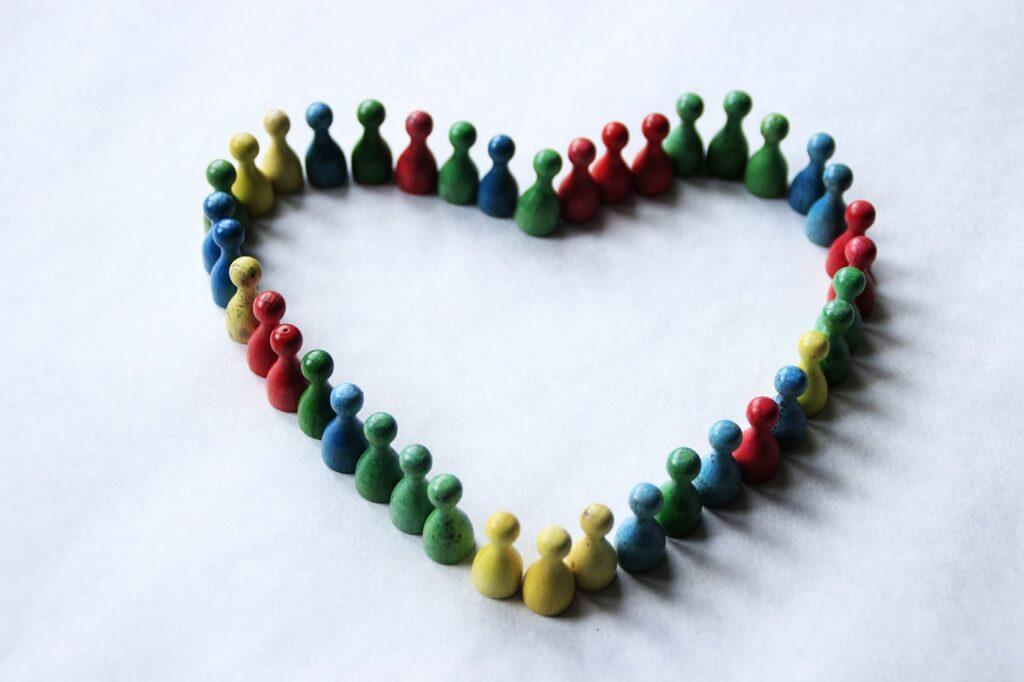 A group of multi-colored human-esque game pieces arranged in a heart shape
