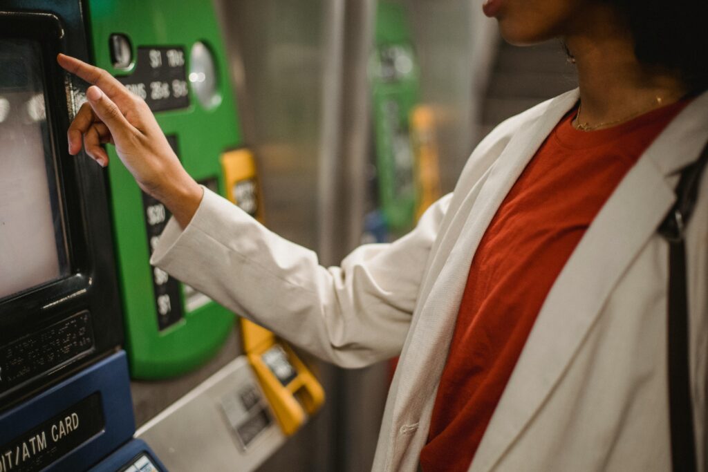 A person presses an on-screen button on a ticketing machine.